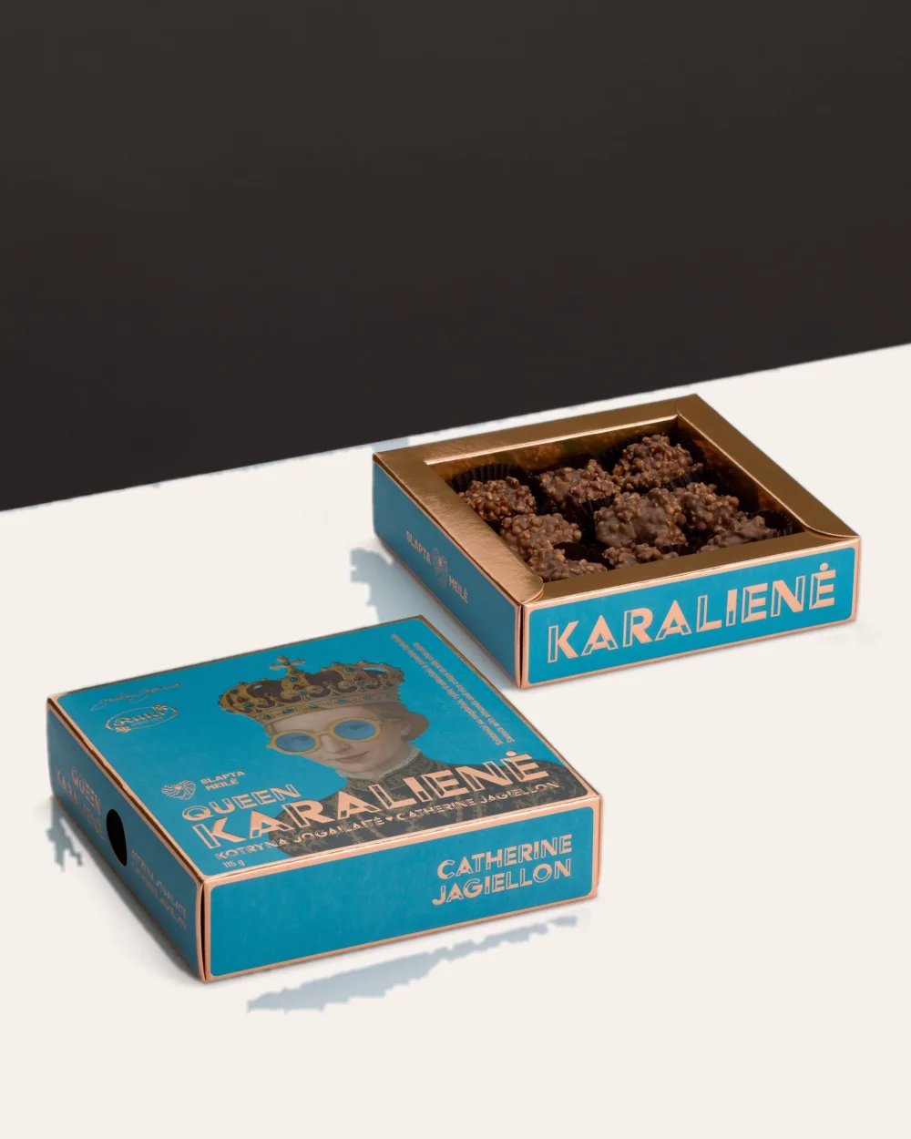 Dvi mėlynos saldainių „Karalienė Kotryna Jogailaitė“ dėžutės, viena su matomais saldainiais