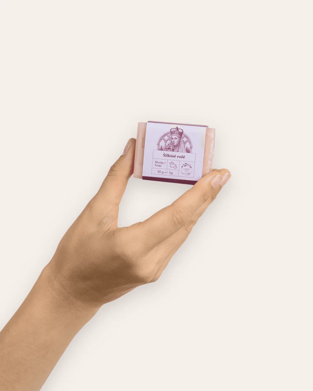 Hand holding a small pink 50 g piece of “Silky Rose” soap bar