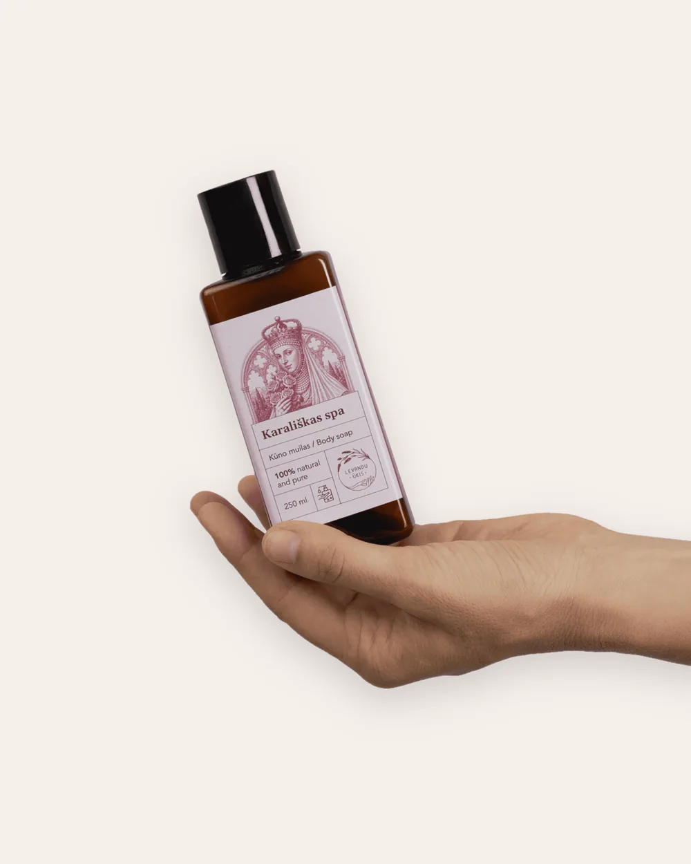 “Royal SPA” rose body wash in a brown bottle tilted on a palm