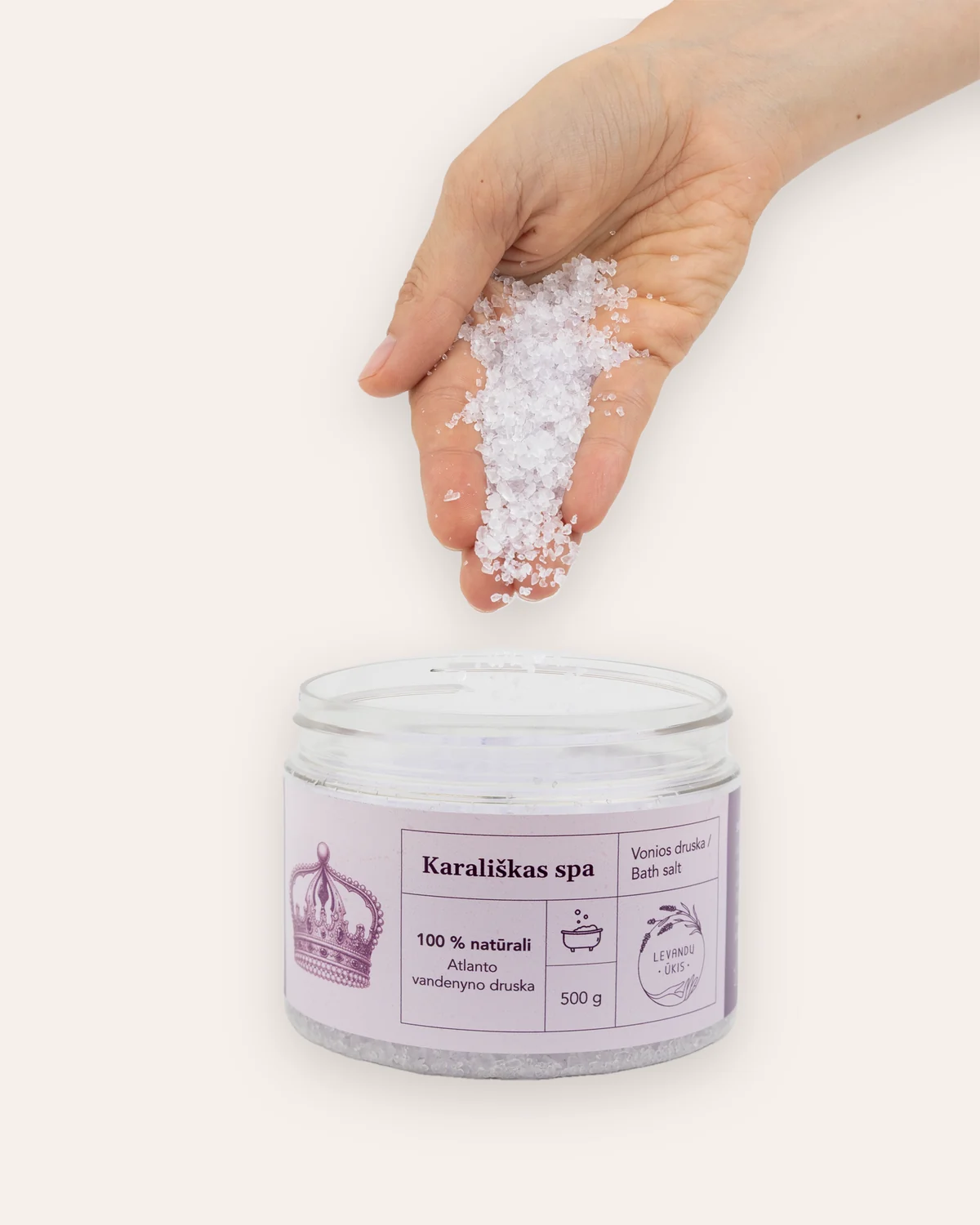 Ranka beria vonios druskos „Karališkas SPA“ kristalus į atidarytą indelį
