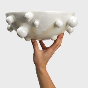 Didelis perlų baltas „Karalienės perlų dubuo“ laikomas viena ranka