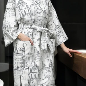 Modelė baltu chalatu kimono „Karališko Vilniaus meilės istorija“ vonioje prie stalviršio, priekis