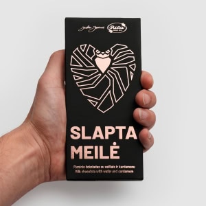 Pieninio šokolado „Slapta meilė“ juoda pakuotė su rausva širdimi rankoje