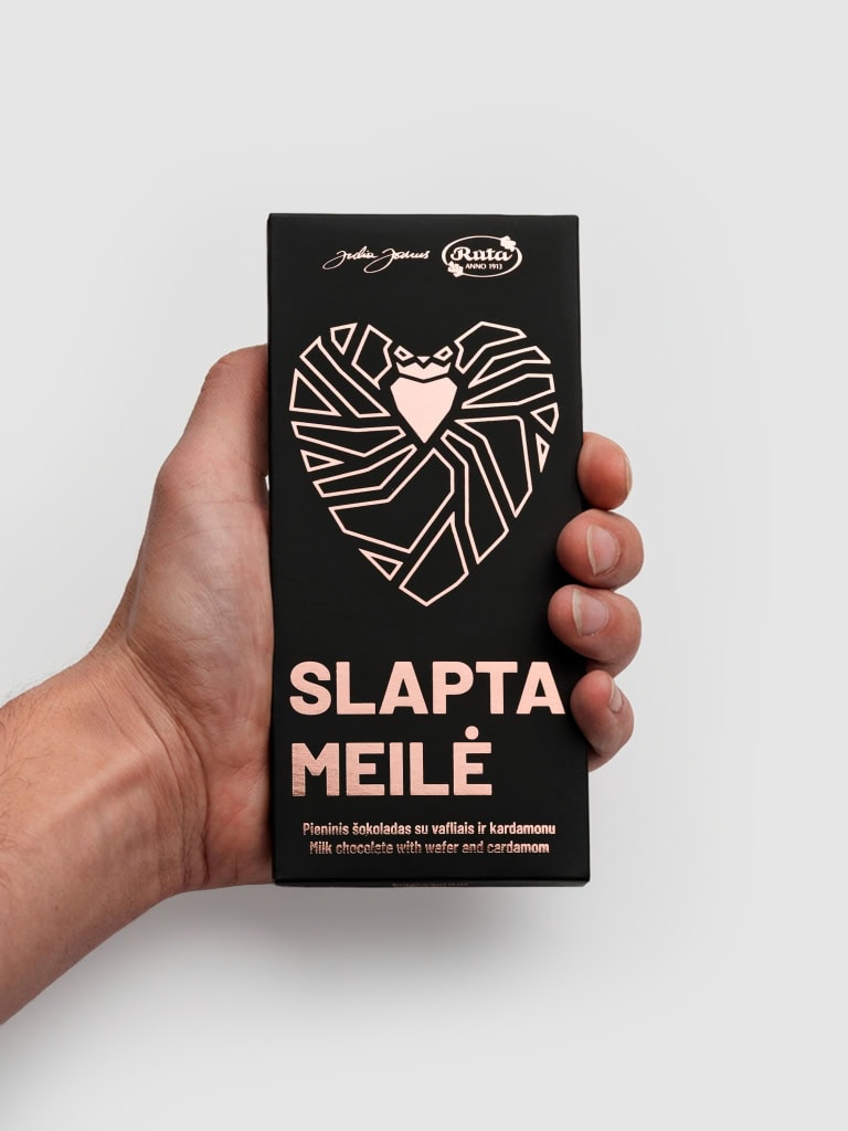 Pieninio šokolado „Slapta meilė“ juoda pakuotė su rausva širdimi rankoje