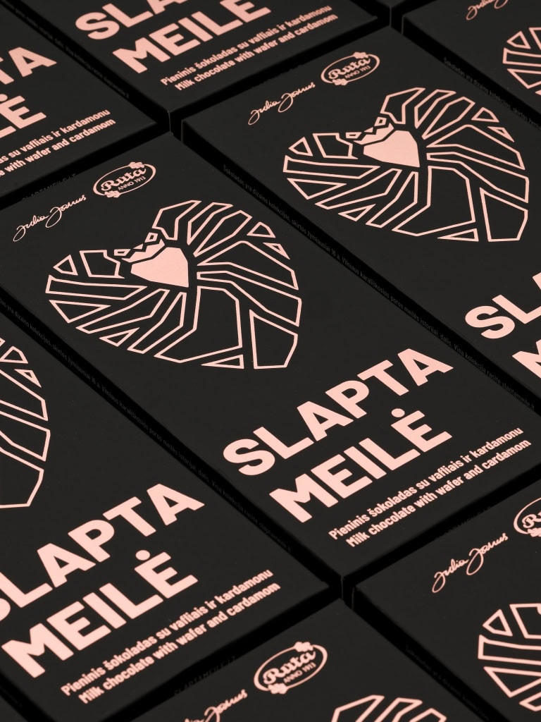 Daug pieninio šokolado „Slapta meilė“ juodų pakuočių su širdies piešiniu, išdėliotų eilėmis