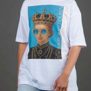 Moteris su baltais marškinėliais „IMIGRANT QUEEN / SWEDEN EDITION“ ir džinsais, ranka kišenėje
