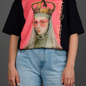Moteris su juodais marškinėliais „REBEL QUEEN“ ir šviesiais džinsais, ranka kišenėje