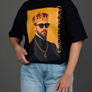 Moteris su juodais marškinėliais „CROWN MOOD“ ir šviesiais džinsais, ranka kišenėje