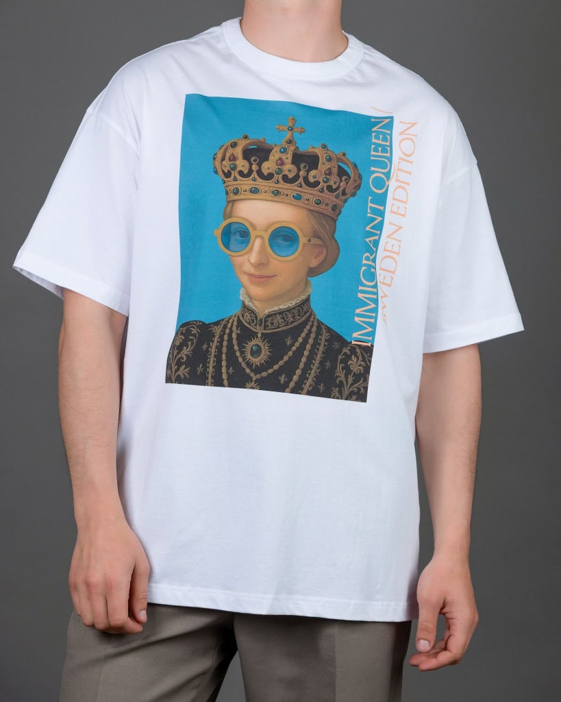 Vyras su baltais marškinėliais „IMIGRANT QUEEN / SWEDEN EDITION“, rankos nuleistos
