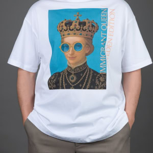 Vyras su baltais marškinėliais „IMIGRANT QUEEN / SWEDEN EDITION“, rankos kišenėse