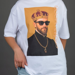 Moteris vilki baltus marškinėlius „CROWN MOOD“ su portretu oranžiniame fone ir džinsus