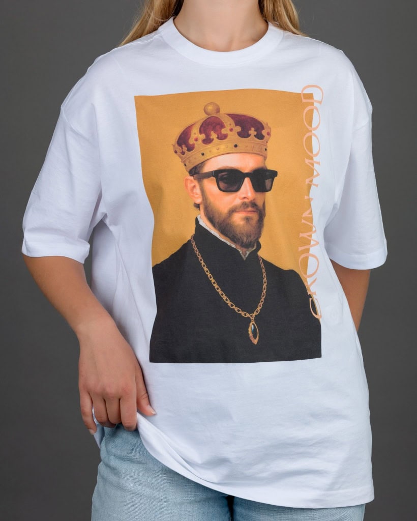 Moteris vilki baltus marškinėlius „CROWN MOOD“ su portretu oranžiniame fone ir džinsus