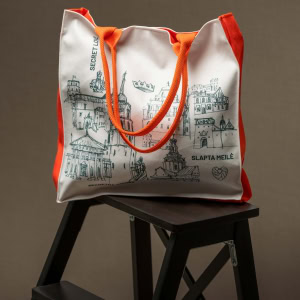 Rankinė „Karališkas Vilnius“ su oranžinėmis rankenomis ant tamsios kėdutės