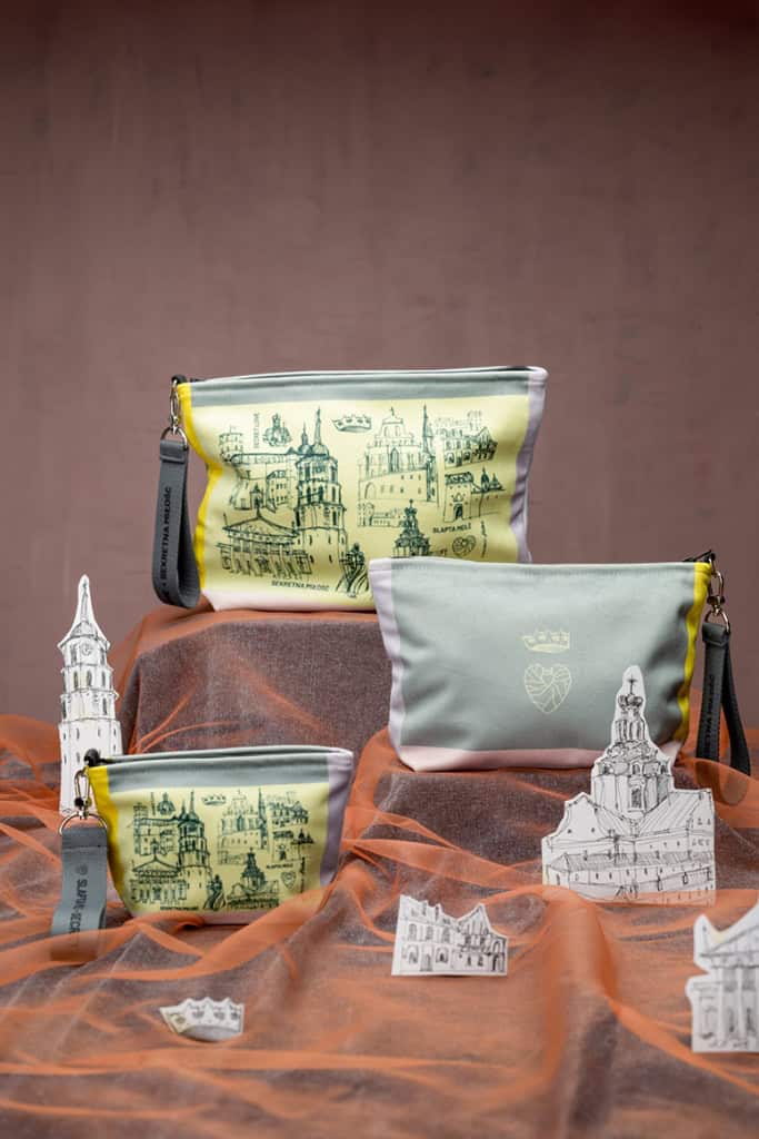 Spalvotos kosmetinės „Spalvotas Karališkas Vilnius“ tarp Vilniaus pastatų maketų ant oranžinio audinio