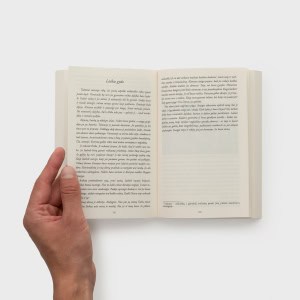 Ranka prilaiko atverstą knygą „Kotryna Jogailaitė. Rožės ir akmens karalienė“