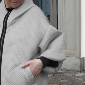 Pilko džemperio „Karalienė maištininkė“ dygsniuotas audinys ir kišenė su ranka iš arti