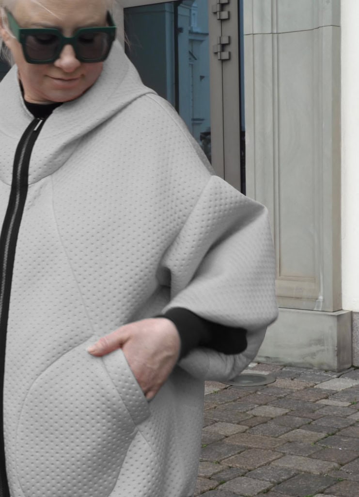 Pilko džemperio „Karalienė maištininkė“ dygsniuotas audinys ir kišenė su ranka iš arti