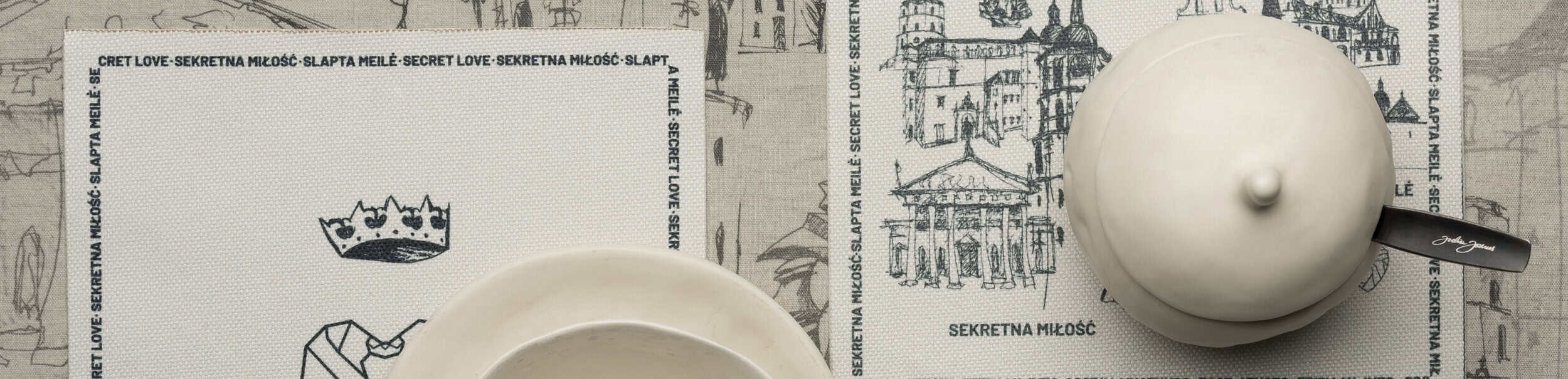 Kolekcijos „Karališkas Vilnius“ juosta: baltas puodelis ir arbatinukas ant padėkliukų su piešiniais