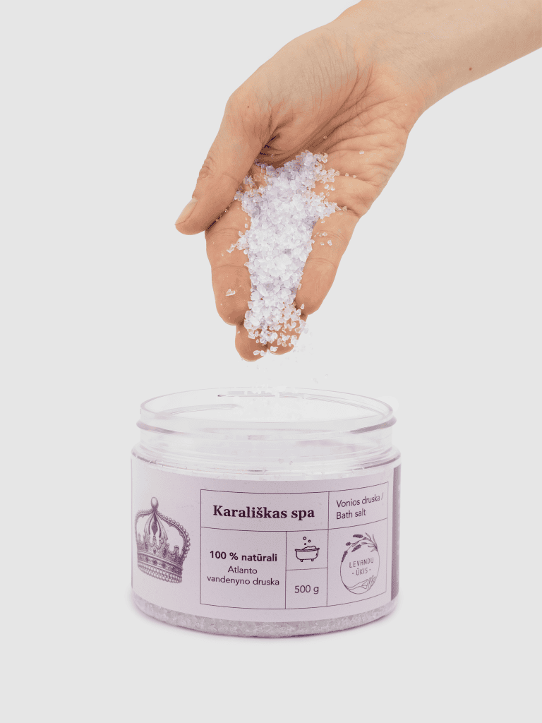 Ranka beria vonios druskos „Karališkas SPA“ kristalus į atidarytą indelį