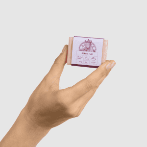 Ranka laiko mažą rausvą kieto muilo „Šilkinė rožė“ 50 g gabalėlį