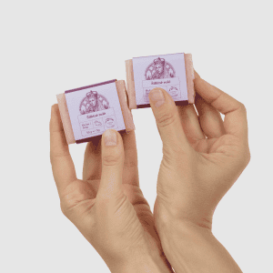 Dvi rankos laiko du mažus kieto muilo „Šilkinė rožė“ 50 g gabalėlius