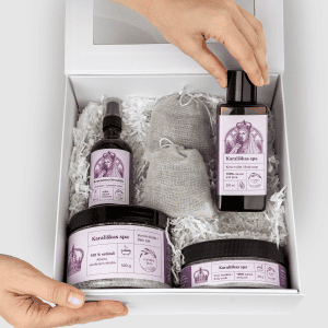 Rankos deda buteliuką į dovanų rinkinį „Karališkas SPA“ su levandų produktais baltoje dėžėje